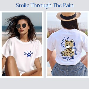 Puede incluir: Dos mujeres con camisetas blancas con dise&ntilde;os gr&aacute;ficos diferentes. El dise&ntilde;o de la camiseta de la izquierda es una cara sonriente azul con la palabra "Smile" encima. El dise&ntilde;o de la camiseta de la derecha es un osito de peluche de dibujos animados con las palabras "Smile Through The Pain" alrededor.