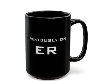 May include: Black ceramic coffee mug with white text that reads "Previously on ER".