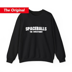 May include: Black sweatshirt with the text "SPACEBALLS THE SWEATSHIRT" in white block letters. The words are centered on the front of the long-sleeved crew neck sweatshirt. A red rectangle with the words "The Original" is in the upper left corner.