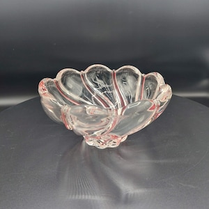 May include: A clear glass bowl with a scalloped edge and red lines. The bowl is sitting on a black surface.