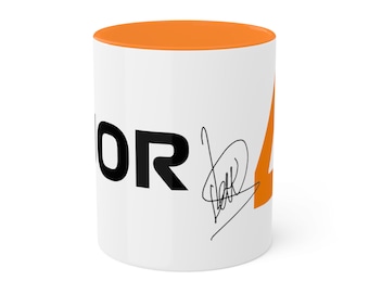 May include: White ceramic mug with an orange rim. The mug features a black graphic of the word "NOR" and the number "4" in orange. A black signature is below the word "NOR".