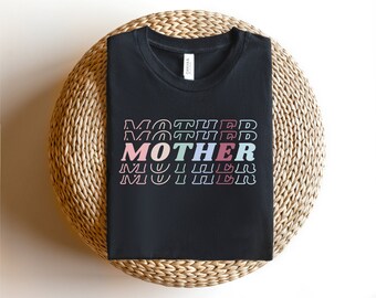 May include: Black t-shirt with the word "MOTHER" repeated in a stacked design. Each word is in a different pastel color, including pink, green, blue, and red.