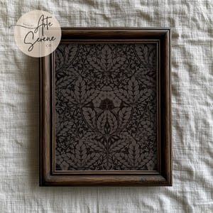 Può includere: Una cornice in legno marrone scuro con una stampa floreale in bianco e nero all'interno. La stampa presenta un motivo ripetitivo di foglie e fiori. La cornice è realizzata da "After Serene Co."