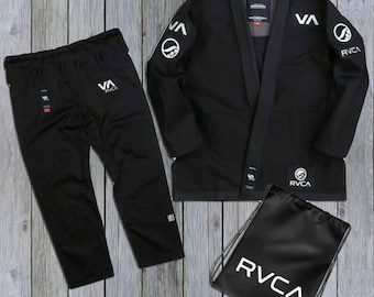 May include: A black martial arts uniform set, including a jacket, pants, and drawstring bag. The jacket and pants feature the "RVCA" logo in white. The jacket has white accents and patches. The drawstring bag also displays the "RVCA" logo.