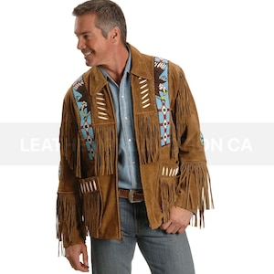 Puede incluir: Una chaqueta de gamuza marrón con flecos y diseños de águilas con cuentas. La chaqueta tiene una cremallera y un cuello de pie.