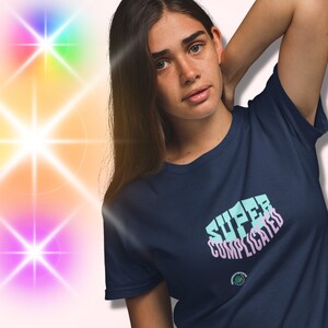 Op de afbeelding: Een donkerblauw t-shirt met de tekst "SUPER COMPLICATED" in lichtblauw en roze.