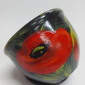 May include: A hand-painted, small wooden bowl with a black exterior. The bowl features a vibrant red poppy flower design with green and yellow accents. The bowl is likely used for serving or display.