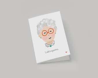 May include: A white card with a watercolor illustration of a woman with gray hair, orange glasses, and a green necklace. The text "Lieblingsoma" is printed below the illustration.
