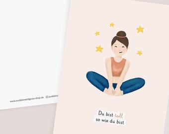 May include: A pink card with a cartoon illustration of a person sitting in a yoga pose with their legs crossed. The person is wearing a peach tank top and blue jeans. There are five yellow stars around the person. The text "Du bist toll so wie du bist" is written in black at the bottom of the card.