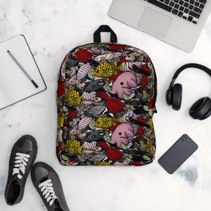 May include: A backpack with a colorful pattern of cartoon fish and other sea creatures. The backpack has a black top handle and straps. The background is white with a laptop, headphones, a phone, a notebook, and shoes.