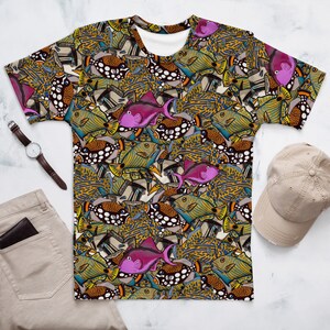 May include: A men's t-shirt with a colorful pattern of fish. The fish are in various shades of blue, green, yellow, orange, and pink. The background is a dark brown color.
