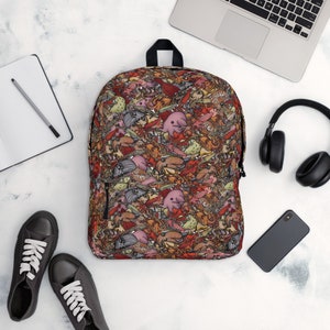 May include: A red backpack featuring a colourful pattern of various sea creatures. The design includes fish, jellyfish, seahorses, and other marine life.
