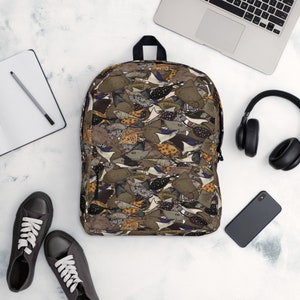 May include: A brown, black, and white patterned backpack with a design of stingrays. The backpack has a zipper closure and adjustable straps.