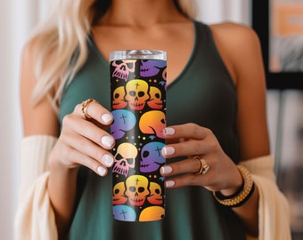 May include: A stainless steel tumbler with a black background and a colorful pattern of skulls and crossbones. The tumbler is approximately 20 ounces in size.