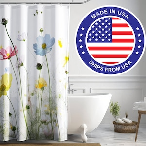 May include: White shower curtain featuring a floral print of colourful cosmos flowers. The shower curtain has a white background with green stems and leaves. The text "Made in USA Ships from USA" is on a blue circle with a red, white and blue American flag in the centre.