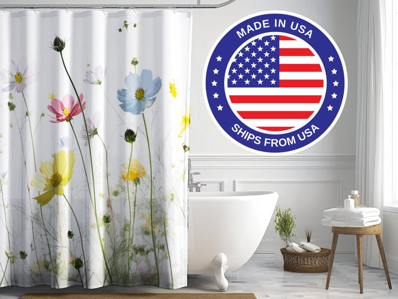 May include: White shower curtain featuring a floral print of colourful cosmos flowers. The shower curtain has a white background with green stems and leaves. The text "Made in USA Ships from USA" is on a blue circle with a red, white and blue American flag in the centre.
