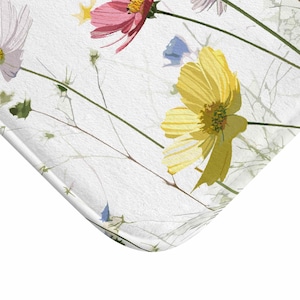 May include: A white background with a floral pattern featuring pink, yellow, and blue flowers with green stems.