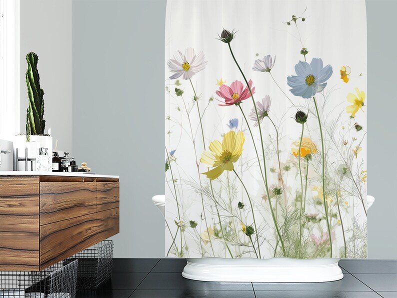 May include: A white shower curtain with a floral print featuring pressed flowers in shades of pink, yellow, blue, and white. The flowers are arranged in a random pattern on a white background.
