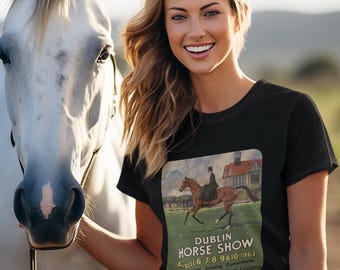 Puede incluir: Camiseta negra con un cartel vintage del Dublin Horse Show que muestra un jinete a caballo. Una mujer sonríe junto a un caballo blanco. El cartel incluye el texto "DUBLIN HORSE SHOW August 6, 7, 8, 9 & 10, 1963".