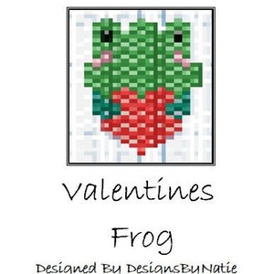 May include: A pixel art design of a green frog holding a red heart. The design is titled "Valentines Frog" and is designed by DesignsByNatie.