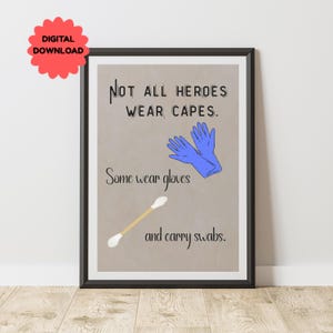 Op de afbeelding: Ingelijste print met de tekst "Niet alle helden dragen capes. Sommigen dragen handschoenen en dragen swabs." De afbeelding bevat blauwe handschoenen en een wattenstaafje op een bruine achtergrond. Een rode "Digital Download" sticker staat linksboven.