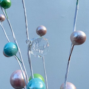 May include: A white twig arrangement with pastel coloured ornaments and a clear crystal hanging from the centre.
