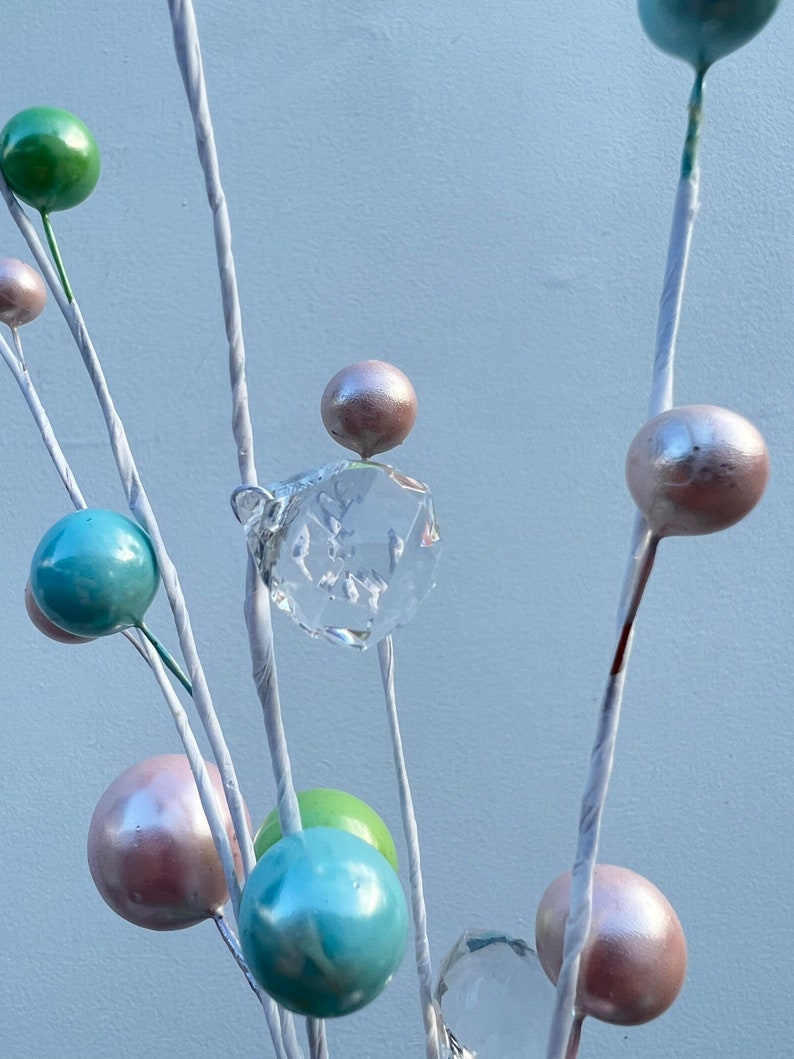 May include: A white twig arrangement with pastel coloured ornaments and a clear crystal hanging from the centre.