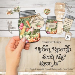 May include: A printable paper craft project featuring mason jar illustrations filled with colorful vegetables, including carrots, corn, and tomatoes. The set includes decorative tags, paper clips, and text reading Tended Things Hidden Paperclip Secret Note Mason Jar, designed for 8.5 inch by 11 inch letter paper.