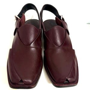 May include: Burgundy leather sandals with a square toe. The sandals have a woven vamp and an ankle strap with a buckle. The soles are dark, and the style is traditional. The sandals are suitable for everyday wear.