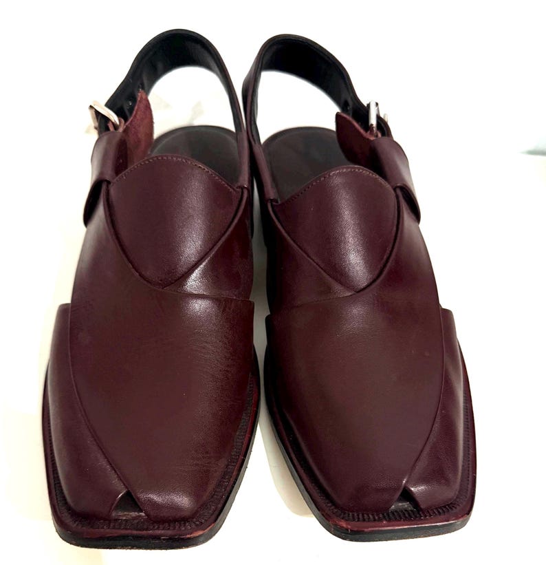 May include: Burgundy leather sandals with a square toe. The sandals have a woven vamp and an ankle strap with a buckle. The soles are dark, and the style is traditional. The sandals are suitable for everyday wear.