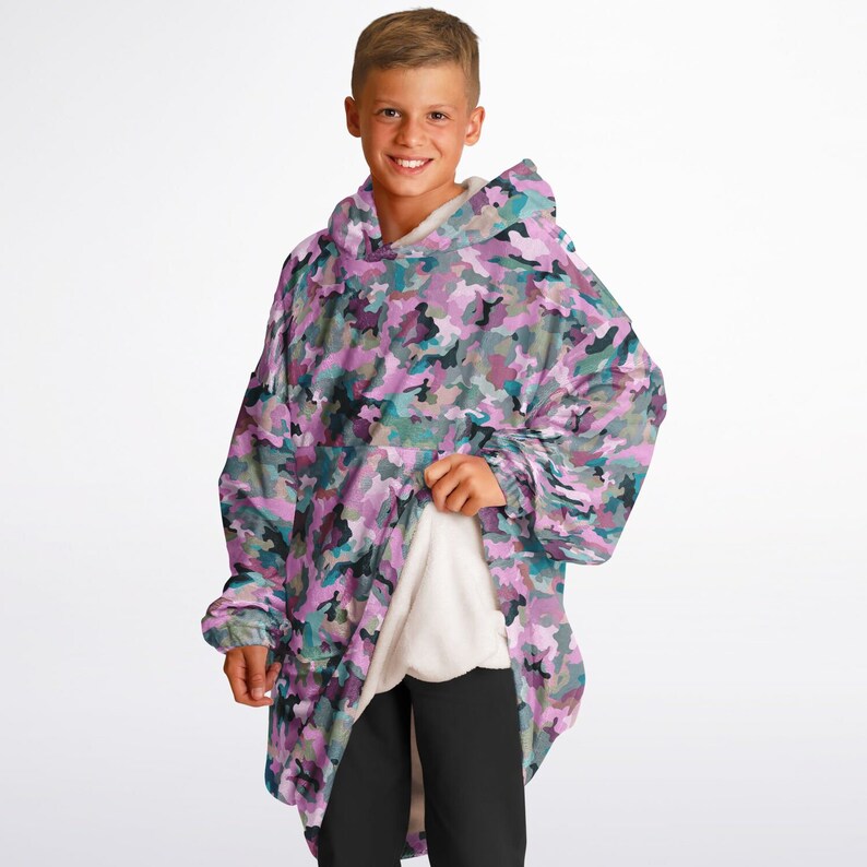 May include: A pink and green camouflage print oversized hoodie with a hood. The hoodie is made of soft fleece and has a relaxed fit.