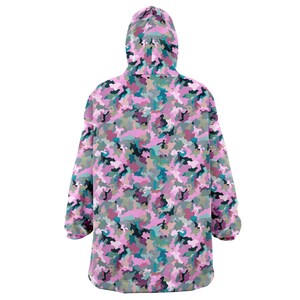 May include: A pink, green, and blue camouflage print hooded blanket. The blanket is made of soft fleece and is perfect for snuggling up on the couch.