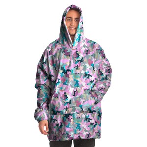 May include: A pink, blue, and green camouflage print oversized hoodie with a kangaroo pocket. The hoodie has a drawstring hood.