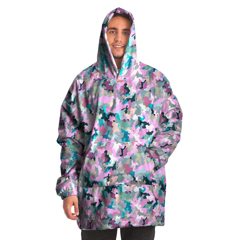 May include: A pink, blue, and green camouflage print oversized hoodie with a kangaroo pocket. The hoodie has a drawstring hood.
