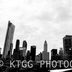 May include: Black and white photograph of the Chicago skyline with tall buildings and a cloudy sky. The text "KTGG PHOTOGRAPHY" is at the bottom of the image.