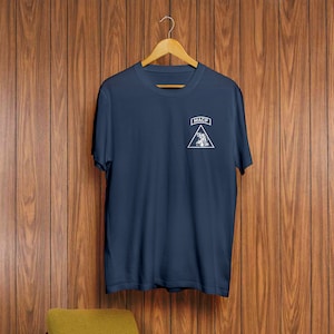 May include: A navy blue t-shirt with a white patch on the left chest. The patch is a triangle with the text "MACP" inside.