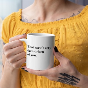 Peut inclure: Une tasse en céramique blanche avec du texte noir qui dit "That wasn't very data driven of you."