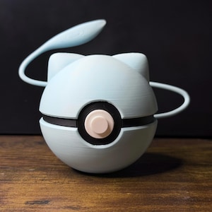 May include: A light blue, spherical object with a black band and a central button. It has two curved, white antennae and a leaf-shaped element extending from the top. The item is likely a decorative or functional piece.