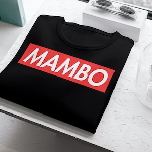 May include: Black t-shirt with a red rectangle and the word "MAMBO" in white letters.
