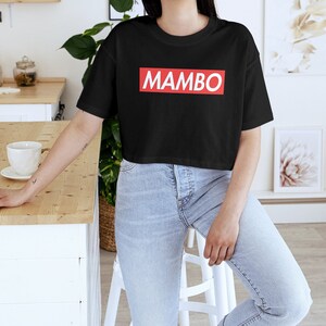 May include: A black cropped t-shirt with a red box and the word "MAMBO" in white letters.