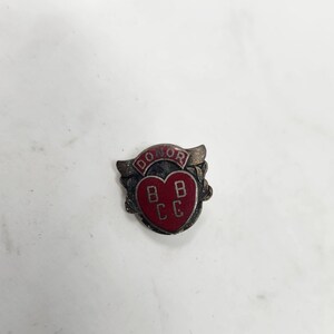 May include: A red heart-shaped pin with the word "DONOR" in a curved banner above it. The heart has the letters "BBCC" inside it.