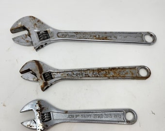 May include: Three adjustable wrenches with silver metal finishes and rust spots. The wrenches are labeled "10 in - 250 mm Crescent", "AWB 8" HEAVY Great Neck BUTN", and "10 in - 250 mm Crescent".
