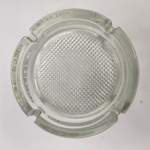 May include: A clear glass ashtray with a textured, diamond-shaped pattern on the bottom.
