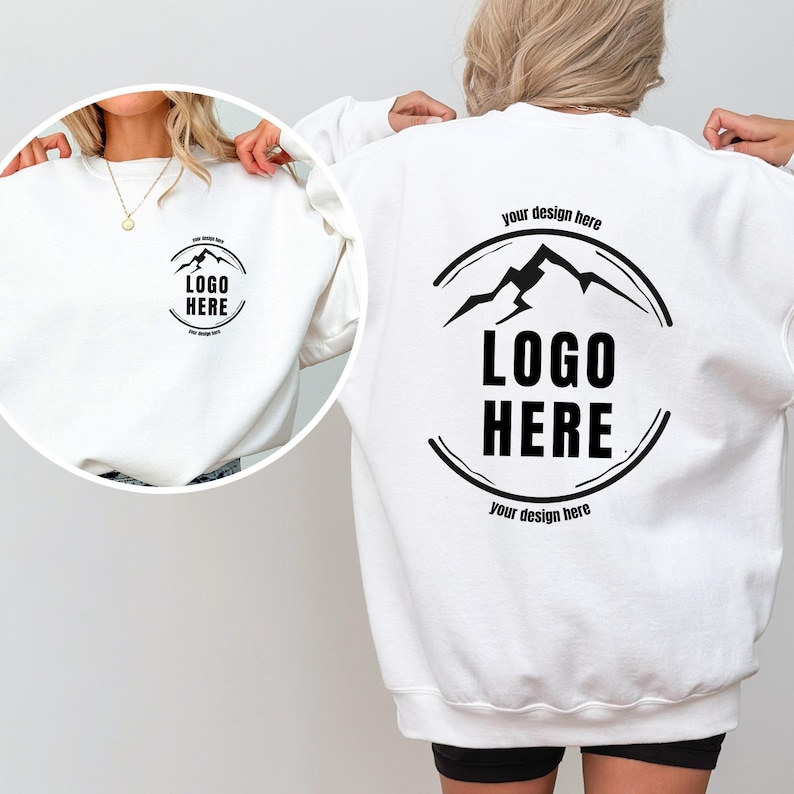 May include: White sweatshirt with a black mountain logo and the text "LOGO HERE" on the back. The front of the sweatshirt has a smaller black circle with the text "LOGO HERE" inside.
