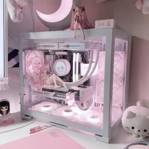 Może przedstawiać: Biała obudowa komputera z przezroczystym panelem bocznym, prezentująca niestandardowy komputer w kolorze różowym i białym z podświetleniem RGB. Obudowa jest ozdobiona figurkami i akcesoriami inspirowanymi anime.