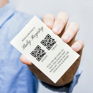 May include: White card with the text "Jessa & Michael's Baby Registry" and two QR codes labeled "Amazon" and "Target". The text below the QR codes reads "Scan the QR codes to view the online baby wish list. Thank you for your love & support."