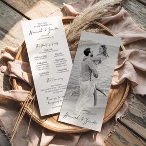 May include: Wedding program featuring the names "Hannah & Zander" in elegant script. The program includes details of the wedding party, ceremony, and a photo of the couple. The design is simple and classic, with a neutral color palette.