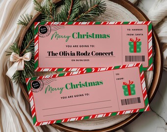 May include: Two rectangular Christmas-themed gift tickets with pink backgrounds and red and green candy cane striped borders. The tickets feature the text Merry Christmas, a Santa Claus postmark, a green gift icon, and a barcode. One ticket is personalized for Hannah from Santa for The Olivia Rodz Concert on 06/06/2025.