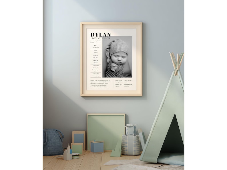 May include: A framed black and white print featuring a baby's photo and birth details. The print is displayed on a light blue wall, with a teepee and toys in the foreground. The text on the print reads "DYLAN LEON ANDERSON".