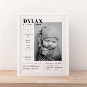 May include: A framed black and white print featuring a baby's portrait. The print includes the baby's name, birth date, time, weight (8lbs 10oz), and length (21 inches). The baby is wearing a knitted hat and wrapped in a blanket.
